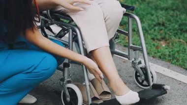 Tekerlekli sandalyede oturan ve bacağını...