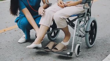 Kadın tekerlekli sandalyede oturuyor ve arkadaşıyla konuşuyor.