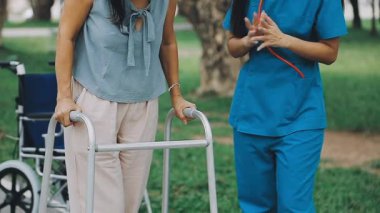 Engelli tekerlekli sandalyeli bir kadın parkta yürüyor. Revirde hemşiresiyle birlikte tekerlekli sandalyede..