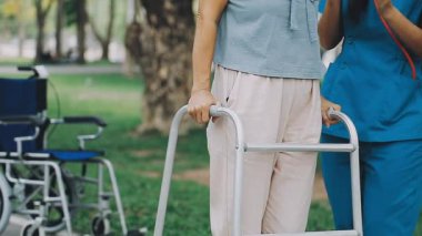 Parkta hemşireyle tekerlekli sandalyedeki kadın.