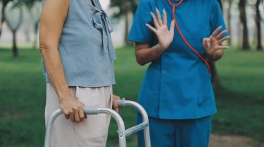 Kadın doktor kıdemli hastaya yürümesi için yardım ediyor