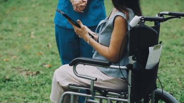 Tekerlekli sandalyedeki genç bayan hasta dijital tablet kullanıyor.