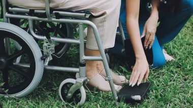 Tekerlekli sandalyedeki kadın parkta koltuk değnekleriyle dinleniyor..