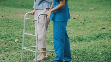 Parkta hemşireyle tekerlekli sandalyedeki genç kadın.