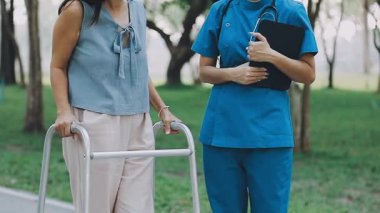 Genç hemşire ve hemşire hemşiresiyle parkta yürüyorlar.