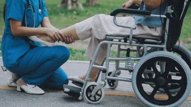 Hastanedeki hastayla tekerlekli sandalyede yürüyen Asyalı kadın doktor.
