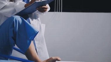 Mavi üniformalı kadın doktor ve elinde not panosu tutan eldivenler.