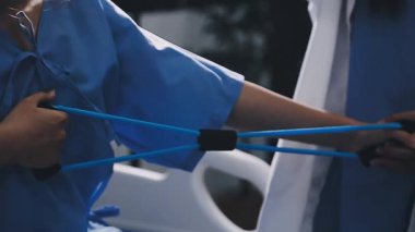 Mavi üniformalı doktor fizik tedavi uyguluyor.