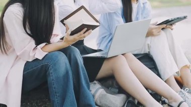 Kampüste oturup dizüstü bilgisayar kullanan bir grup öğrenci.