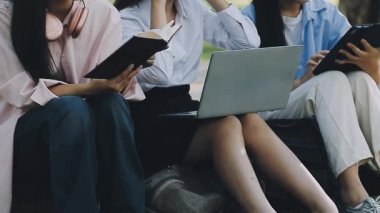 Genç kadınlar dizüstü bilgisayar kullanıyor ve parkta oturuyor..