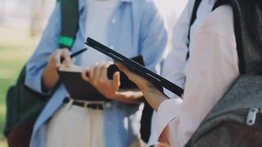 Genç Asyalı öğrenciler bir kitap tutuyor ve birlikte okuyorlar, öğrenim ve eğitim.