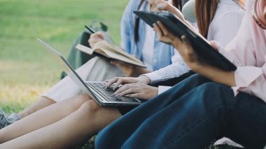 Parkta dizüstü bilgisayar kullanan bir grup insan.