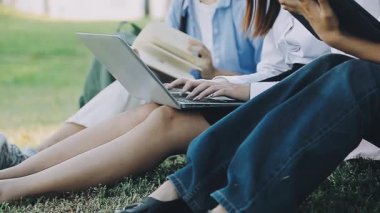 Genç kadın parkta oturuyor ve dizüstü bilgisayar kullanıyor.