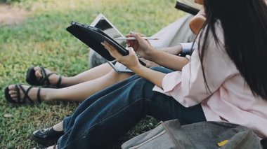 Parkta dijital tablet kullanan genç Asyalı kadın