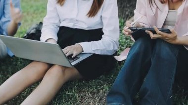 Parkta dizüstü bilgisayarda çalışan genç iş adamları