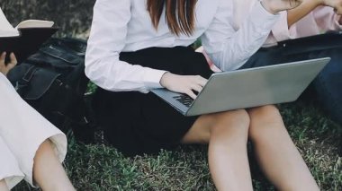 Genç iş kadını dizüstü bilgisayar kullanıyor ve arkadaşlarıyla konuşuyor.