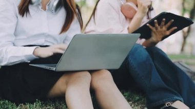 İki güzel kadın bankta oturuyor, dizüstü bilgisayarlarıyla çalışıyor ve çalışıyorlar.