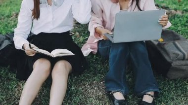 Genç öğrenciler dizüstü bilgisayarla çalışıyorlar ve parkta çalışıyorlar.