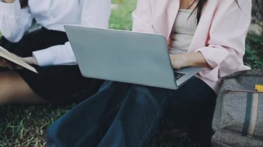 Parkta dizüstü bilgisayarı ve defteri olan genç bir kız öğrenci.