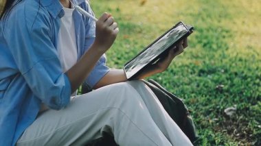 Yaz parkında elinde tabletle beyaz gömlekli bir kız..