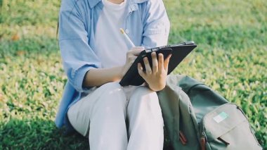 Genç kız çimlerin üzerinde oturuyor ve kitap okuyor.