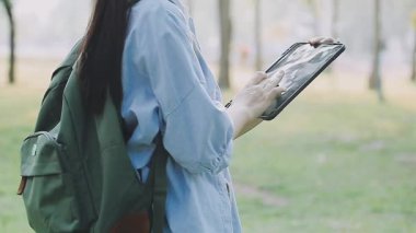 Kadın parkta, açık havada dijital tablet kullanıyor