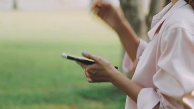 Parkta akıllı telefonu olan genç bir kız.