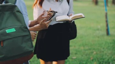 Sırt çantalı beyaz gömlekli kız ormanda kitap okuyor.