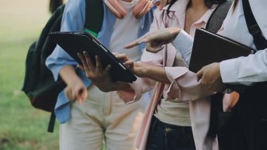 Elinde tabletle parkta gezen bir grup genç..