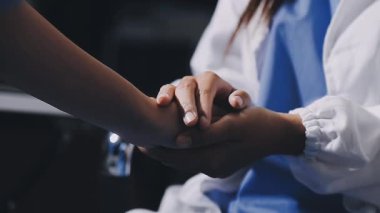 Doktor muayenehanede bir hastanın elini tutuyor.