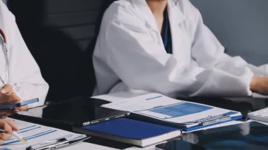 Kapalı - iki doktorun eli kalem tutarken ve not yazarken.