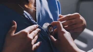 Genç bir doktor steteskoplu bir hastayı muayene ediyor.