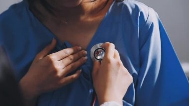 Genç doktor hastanın kalp atışlarını kontrol ediyor.