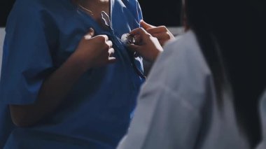 Kadın doktor hastane lobisinde steteskopu inceliyor..