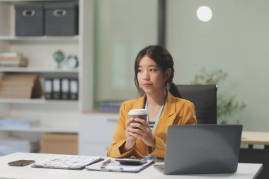 Modern ofis odasında dizüstü bilgisayarla projesinde çalışan çekici genç bir iş kadını..