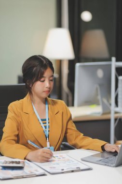 Modern ofis odasında dizüstü bilgisayarla projesinde çalışan çekici genç bir iş kadını..