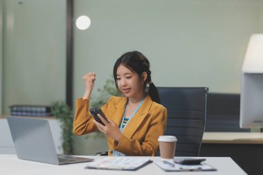 Asyalı iş kadını dizüstü bilgisayar kullanıyor ve ofiste hesap makinesi ile çalışıyor, mali raporu, iş planı yatırımını, mali analiz konseptini analiz etmeyi planlıyor..
