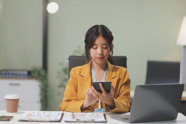 Modern ofis odasında dizüstü bilgisayarla projesinde çalışan çekici genç bir iş kadını..