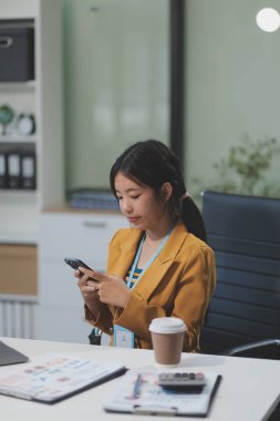 Asyalı iş kadını dizüstü bilgisayar kullanıyor ve ofiste hesap makinesi ile çalışıyor, mali raporu, iş planı yatırımını, mali analiz konseptini analiz etmeyi planlıyor..