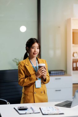 Modern ofis odasında dizüstü bilgisayarla projesinde çalışan çekici genç bir iş kadını..