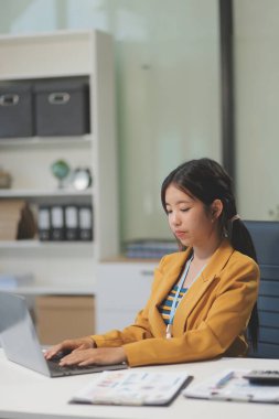 Modern ofis odasında dizüstü bilgisayarla projesinde çalışan çekici genç bir iş kadını..