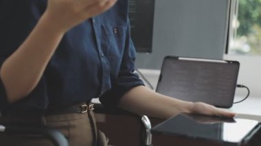 İş adamı elinde tablet bilgisayar tutuyor ve işyerindeki klavyesine yazı yazıyor..