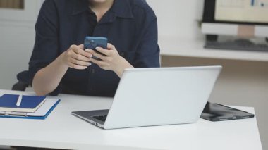 Ofiste dizüstü bilgisayarı ve telefonu olan bir kadın var.