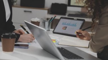 Genç iş kadını ofiste dizüstü bilgisayar ve tablet bilgisayar kullanıyor.