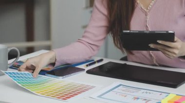 Genç bayan tasarımcı ofiste tablet bilgisayarla çalışıyor.