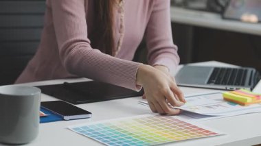 Ofiste grafik tablet bilgisayarı ve renk örneğiyle çalışan genç kadın