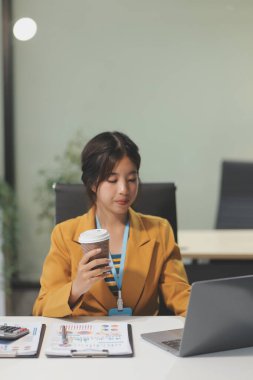 Modern ofis odasında dizüstü bilgisayarla projesinde çalışan çekici genç bir iş kadını..