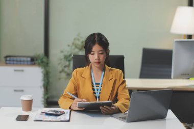 Modern ofis odasında dizüstü bilgisayarla projesinde çalışan çekici genç bir iş kadını..