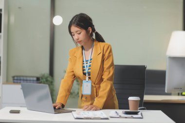 Modern ofis odasında dizüstü bilgisayarla projesinde çalışan çekici genç bir iş kadını..