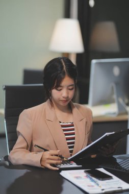 Telework konsepti - Asyalı iş kadını video toplantısına katılmak için dizüstü bilgisayar kullanır ve evdeki dijital tabletine notlar yazar